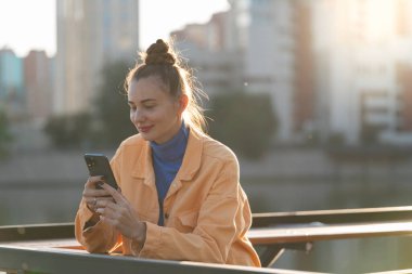 Sonbaharda sokakta elinde akıllı telefon olan genç bir kadın. Yüksek kalite fotoğraf