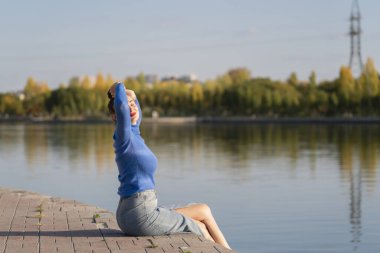 Genç bir kadın setin kenarında nehrin kenarında oturuyor. Kavram: özgürlük, hayatın tadını çıkarmak, kendinle baş başa kalmak. Yüksek kalite fotoğraf