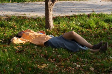 Parktaki yeşil çimlerin üzerinde genç bir kadın yatıyor. Yüksek kalite fotoğraf