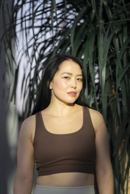 Yeşil tropikal bitkilerin arka planında genç bir Asyalı kadının portresi. Yüksek kalite fotoğraf