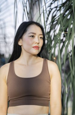 Yeşil tropikal bitkilerin arka planında genç bir Asyalı kadının portresi. Yüksek kalite fotoğraf