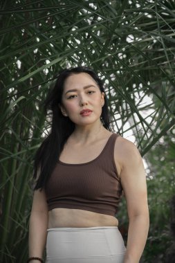 Yeşil tropikal bitkilerin arka planında genç bir Asyalı kadının portresi. Yüksek kalite fotoğraf