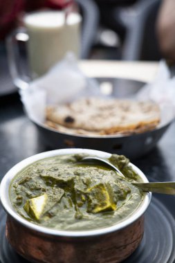 Paneer peynirinden yapılmış, yumuşak baharatlı ıspanak sosuna batırılmış ahşap arka planda bir kase Palak Paneer. Yüksek kalite fotoğraf