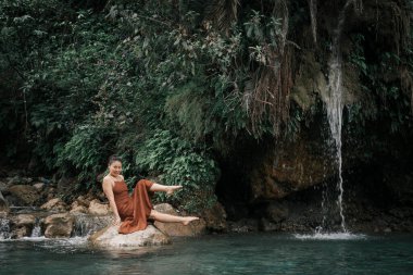 Hindistan, Gizli Şelale. Kahverengi elbiseli Asyalı bir kız, tropiklerin arka planında. Yüksek kalite fotoğraf.