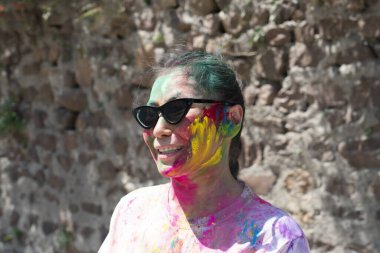 Holi festivali sırasında yüzünde parlak renkler olan Asyalı bir kadın. Hindistan, Rishikesh. Yüksek kalite fotoğraf