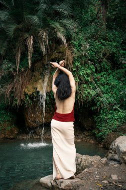 Hindistan, Gizli Şelale. Asyalı bir kız tropiklerin arka planına karşı. Çok kaliteli bir fotoğraf.