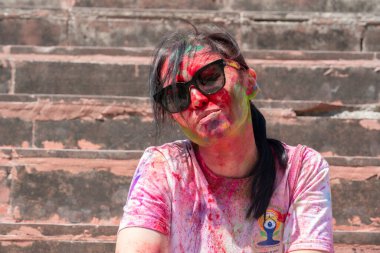 Holi festivali sırasında yüzünde parlak renkler olan Asyalı bir kadın. Hindistan, Rishikesh. Yüksek kalite fotoğraf