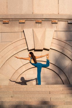 Mavi tulumlu Asyalı bir kadın şehir caddesinde yoga yapıyor. Yüksek kalite fotoğraf