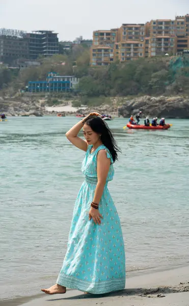 stock image A girl in a blue dress walks on the beach near the Ganges. Rishikesh, India. High quality photo