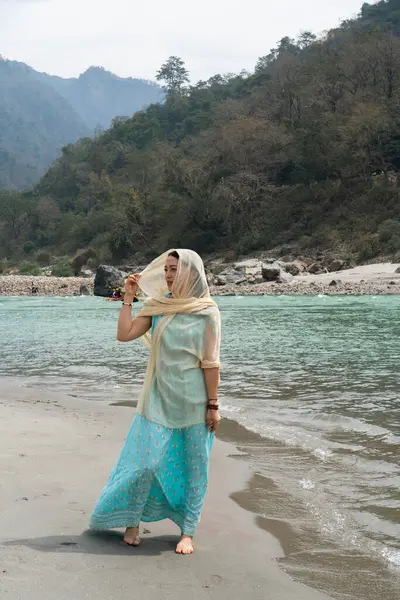 Mavi elbiseli bir kız Ganj yakınlarındaki sahilde yürüyor. Rishikesh, Hindistan. Yüksek kalite fotoğraf