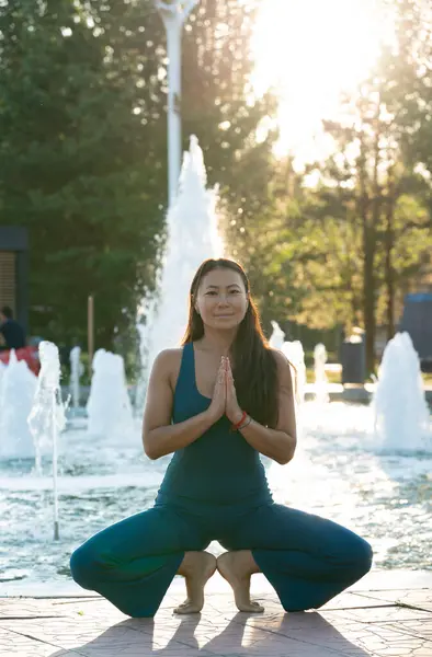 Mavi tulumlu Asyalı bir kadın şehir caddesinde yoga yapıyor. Yüksek kalite fotoğraf