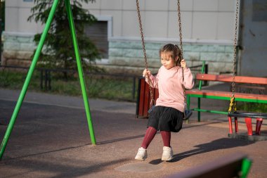 Yedi yaşında bir kız bahçede salıncakta sallanıyor. Yüksek kalite fotoğraf