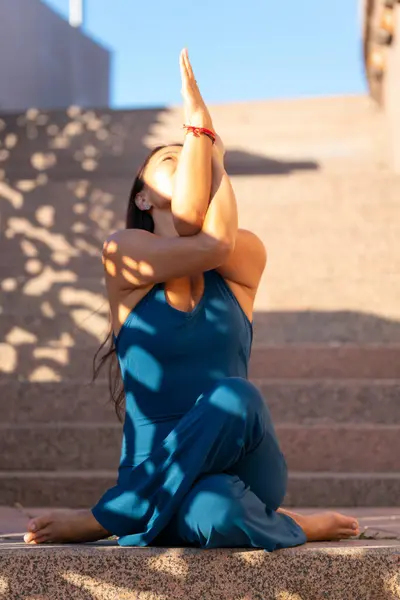 Mavi tulumlu Asyalı bir kadın şehir caddesinde yoga yapıyor. Yüksek kalite fotoğraf
