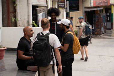 Rishikesh, India, March 24, Male tourists communicate on the city street. High quality photo clipart