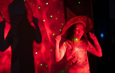 Cadılar Bayramı partisinde 10 yaşında cadı şapkası takan bir kız. Renkli ışıklandırma. Yüksek kalite fotoğraf