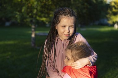 10 ve 3 yaşındaki küçük kızlar sarılıyorlar. Kardeşler arası aşk. Yüksek kalite fotoğraf