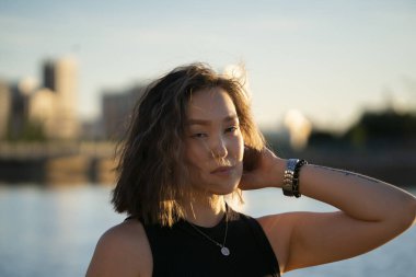 Siyah elbiseli genç Asyalı kadının yaz portresi, arka plan ışığı, altın saat. Yüksek kalite fotoğraf