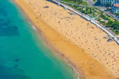 İnsanlar İspanya, San Sebastian 'daki La Concha plajında güneşli bir günün tadını çıkarıyorlar..