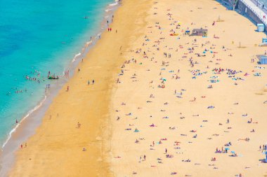 İnsanlar İspanya, San Sebastian 'daki La Concha plajında güneşli bir günün tadını çıkarıyorlar..