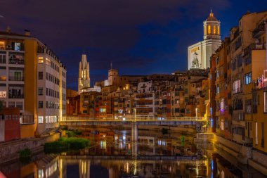 İspanya 'daki Girona katedralinin gece manzarası renkli evlerin arkasında görülüyor..