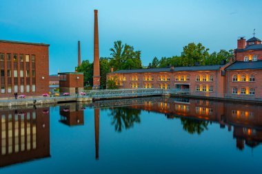 Tampere, Finlandiya 'da Tammerkoski kanalının yanındaki tuğla binaların günbatımı manzarası.