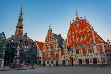 Ratslaukums Meydanı 'nda gün batımı Aziz Peter Kilisesi ve Letonya' nın Riga kentindeki Siyahların Evi ile...