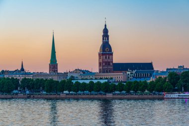 Riga Katedrali 'nin gün batımı manzarası ve Letonya' nın Daugava Nehri 'nin diğer yakasındaki Aziz James Kilisesi...