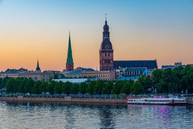 Riga Katedrali 'nin gün batımı manzarası ve Letonya' nın Daugava Nehri 'nin diğer yakasındaki Aziz James Kilisesi...