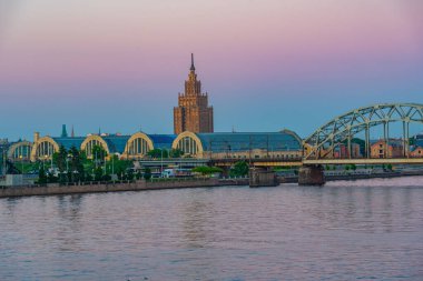Zeplin hangarlarının ve Letonya 'nın başkenti Riga' daki çelik bir demiryolu köprüsünün yanındaki bilim akademisinin günbatımı manzarası..