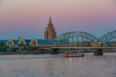 Zeplin hangarlarının ve Letonya 'nın başkenti Riga' daki çelik bir demiryolu köprüsünün yanındaki bilim akademisinin günbatımı manzarası..