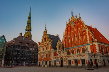 Ratslaukums Meydanı 'nda gün batımı Aziz Peter Kilisesi ve Letonya' nın Riga kentindeki Siyahların Evi ile...