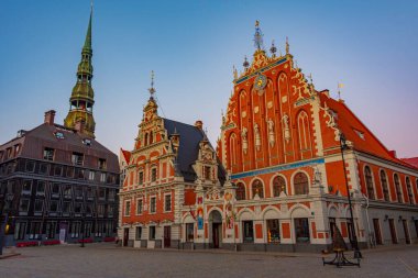 Ratslaukums Meydanı 'nda gün batımı Aziz Peter Kilisesi ve Letonya' nın Riga kentindeki Siyahların Evi ile...