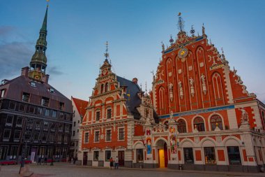 Ratslaukums Meydanı 'nda gün batımı Aziz Peter Kilisesi ve Letonya' nın Riga kentindeki Siyahların Evi ile...