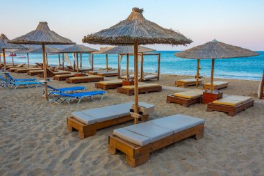 Yunanistan 'ın Girit kentindeki Vai plajında gün batımı şemsiye ve güneşlik manzarası.