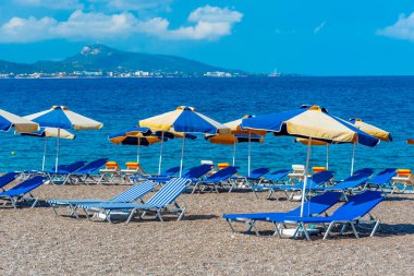 Yunanistan 'ın Rodos kentinde bir plajda güneşlik ve şemsiyeler.