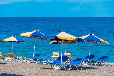 Yunanistan 'ın Rodos kentinde bir plajda güneşlik ve şemsiyeler.
