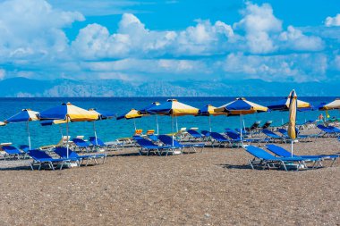 Yunanistan 'ın Rodos kentinde bir plajda güneşlik ve şemsiyeler.