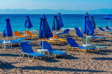 Yunanistan 'ın Rodos kentinde bir plajda güneşlik ve şemsiyeler.