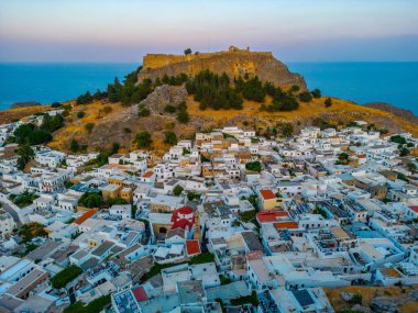 Yunanistan 'ın Rodos adasındaki geleneksel beyaz evlere bakan Lindos Akropolünün günbatımı manzarası.