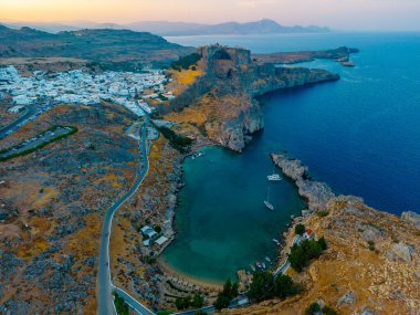 Rodos 'taki Yunan kenti Lindos' taki Saint Paul plajı ve Akropolis 'in günbatımı manzarası.