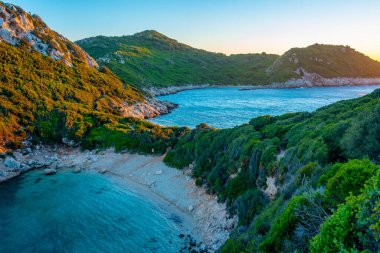 Yunan adası Korfu 'daki Porto Timoni plajının gün batımı manzarası.