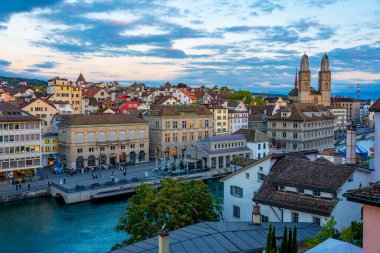 Zuerich 'teki nehir limmatı rıhtımının gün batımı manzarası belediye binası ve İsviçre' deki Grossmuenster katedralinin egemenliğinde..