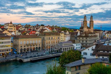 Zuerich 'teki nehir limmatı rıhtımının gün batımı manzarası belediye binası ve İsviçre' deki Grossmuenster katedralinin egemenliğinde..