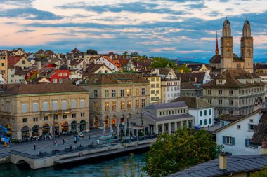 Zuerich 'teki nehir limmatı rıhtımının gün batımı manzarası belediye binası ve İsviçre' deki Grossmuenster katedralinin egemenliğinde..