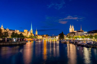 Ünlü Fraumuenster ve Grossmuenster Kiliseleri ve İsviçre Limmat nehri ile Zuerich 'in tarihi şehir merkezinin günbatımı manzarası.
