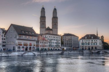 İsviçre 'nin Zürih kentindeki Grossmuenster katedrali ile Limmat nehrinin gün doğumu manzarası.