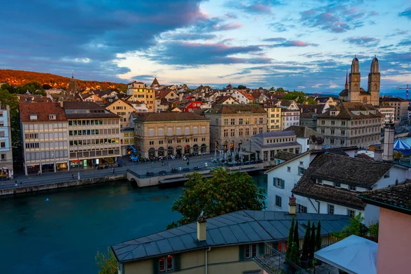 Zuerich 'teki nehir limmatı rıhtımının gün batımı manzarası belediye binası ve İsviçre' deki Grossmuenster katedralinin egemenliğinde..