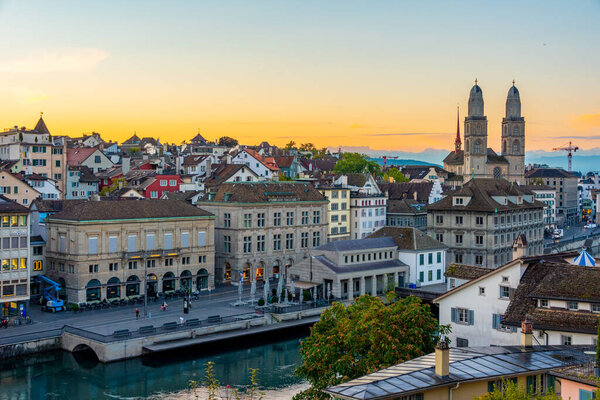 Sunrise view of quay of river limmat in Zuerich dominated by the town hall and Grossmuenster cathedral, Switzerland.