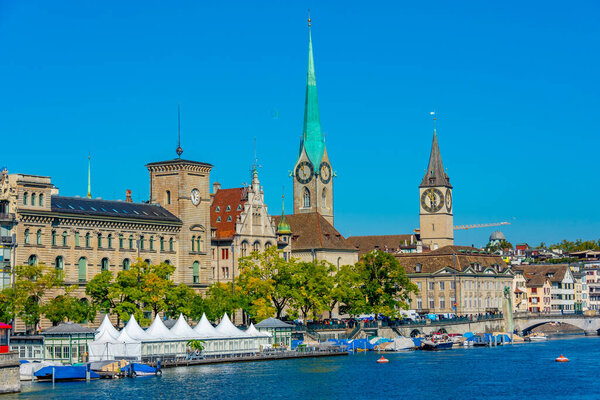 Panoramic view of historic Zuerich city center with famous Fraumuenster Church and river Limmat on a sunny day, Switzerland.