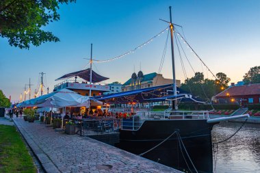 Turku, Finlandiya, 19 Temmuz 2022: Turku, Finlandiya 'da Aura nehri kıyısında demirleyen teknelerin gün batımı manzarası.